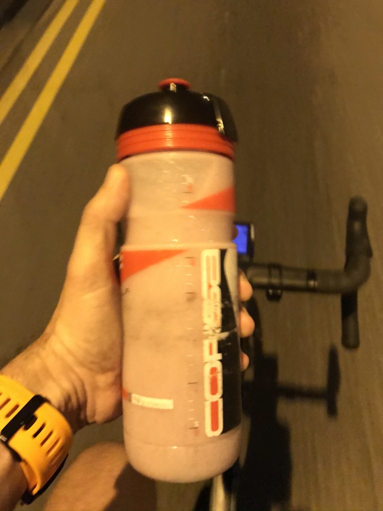 hand holding a bottle while on a bike