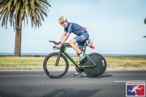 Triathlete on a time trial bike with a disc wheel racing in a tropical setting
