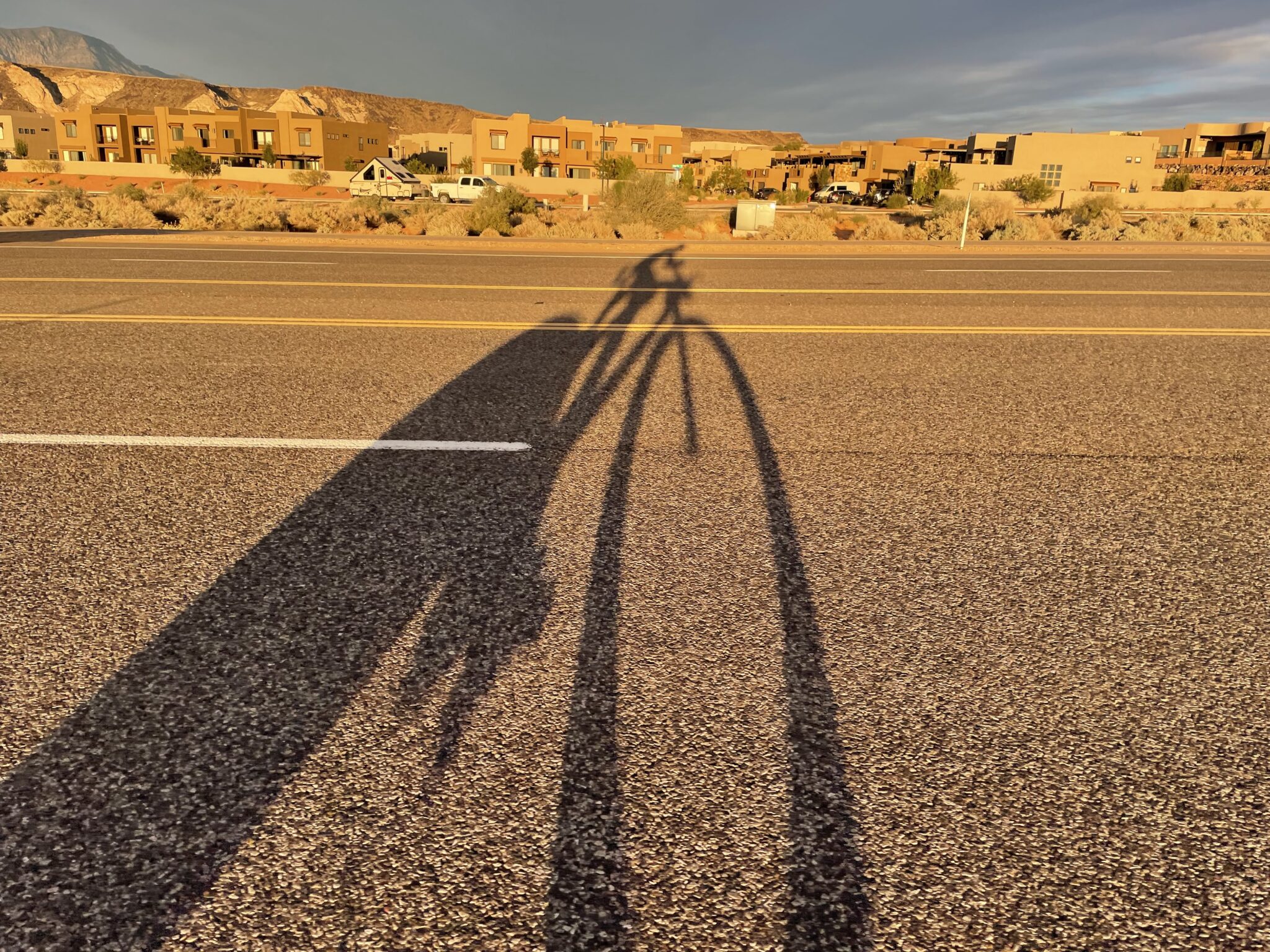 Long shadow of bike on road during sunset